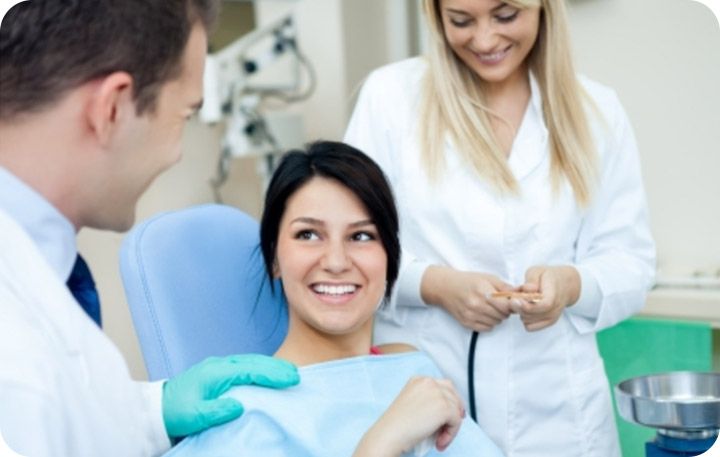 Smiling patient in the dental chair with a dentist and assistant