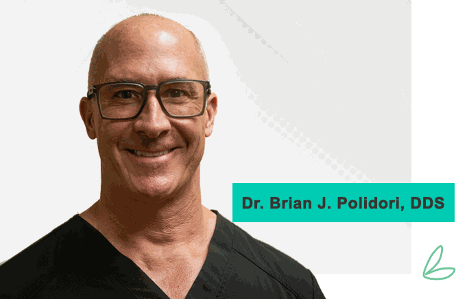 Dr. Brian J. Polidori, DDS, smiling, in dark dental scrubs