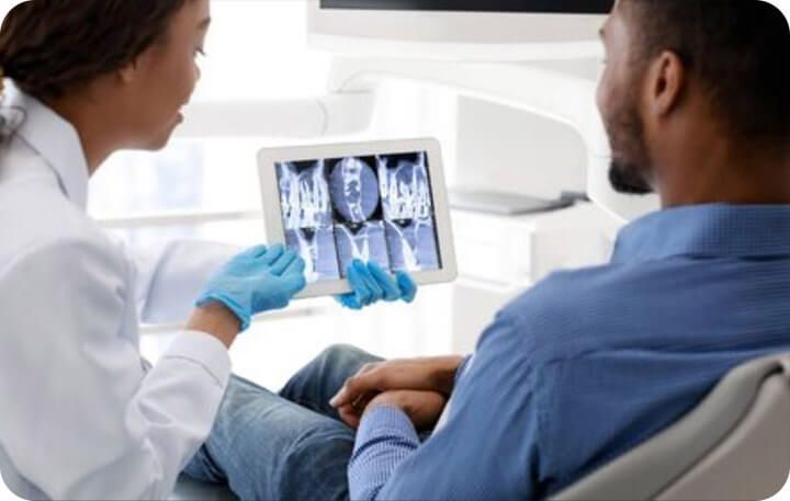 Dental hygienist showing a patient his x-rays on a tablet